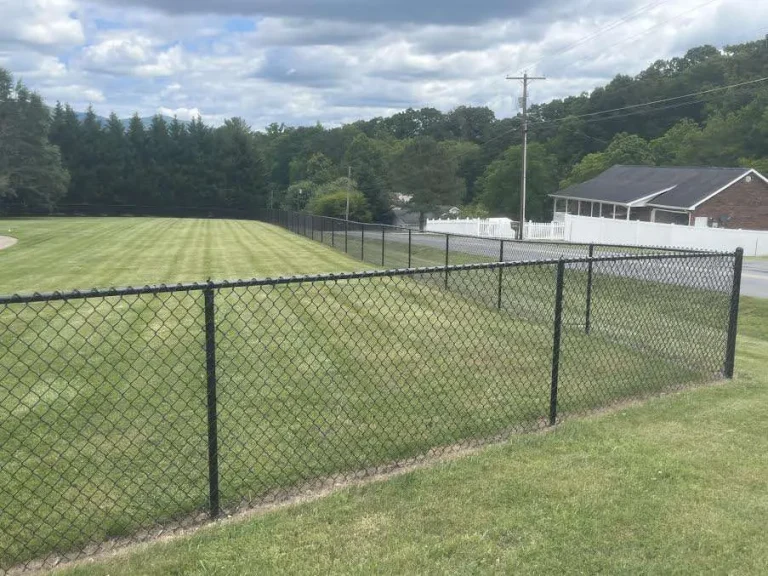 A new, sturdy chain link fence installation in Johnson City, TN, set against a property landscape, combining security with a transparent view, reflecting professional installation and modern design.